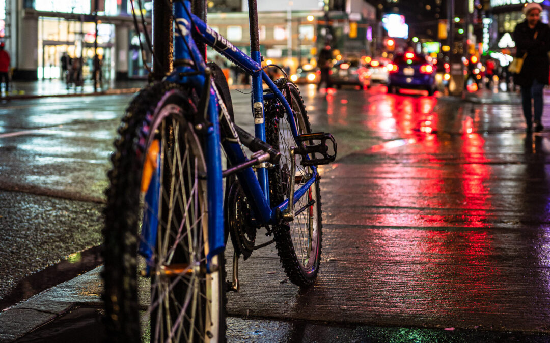 Blue bicycle on rainy Yonge Street at night, red and green neon reflections in wet pavement, colourful Toronto street photography, Fuji X100V