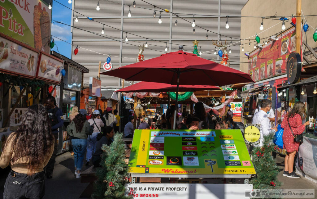 Colourful food market with red umbrella, string lights and vendor stalls on Yonge Street, Fuji X100V