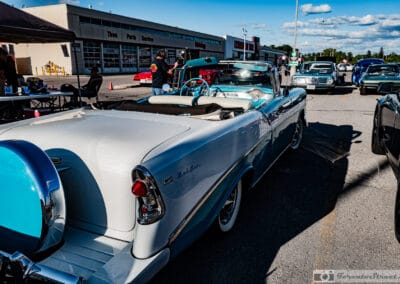 Turquoise-and-white drop-top low in golden side light, 56 DREAM plate, two men talking beside it, Leica Q3