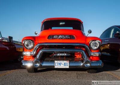 Orange 1957 GMC 9300 Stepside parked front three-quarter at a Richmond Hill cruise night, Leica Q3