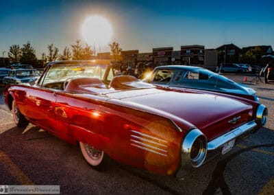 The red convertible against a burning sunset sky, fins and round lamps in silhouette, Leica Q3