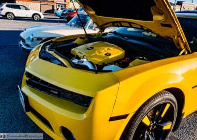 Hood up on the yellow coupe, halo headlights and open engine bay under a blue sky, Leica Q3