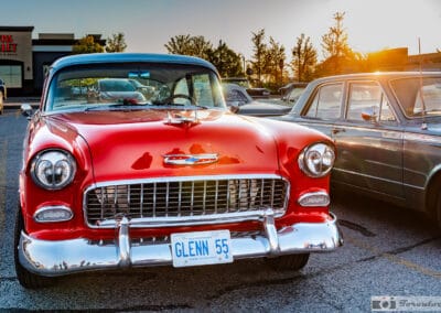 Red-and-white two-tone hardtop at golden hour, GLENN 55 plate, a strip plaza glowing behind, Leica Q3