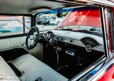 White bucket-seat interior and the Bel Air dash script behind the wheel of a 1955 Chevrolet, Leica Q3