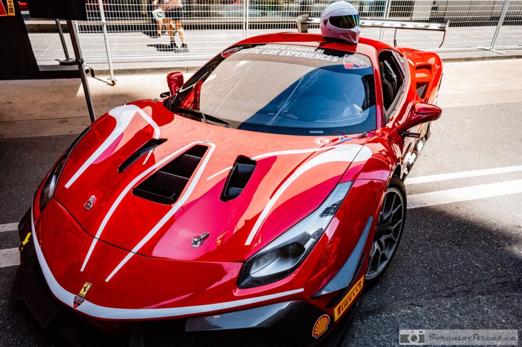 Ferrari 488 Challenge Evo-- Red race car staged with a driver helmet resting on the roof, white pinstripes on a glossy hood, Leica Q3