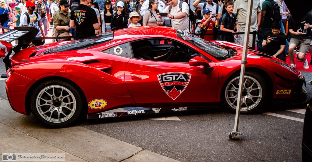 Ferrari 488 Challenge Evo,_-1000980-2 Crowd lifting phones around a red track car with a tall rear wing at the Yorkville car show, Leica Q3