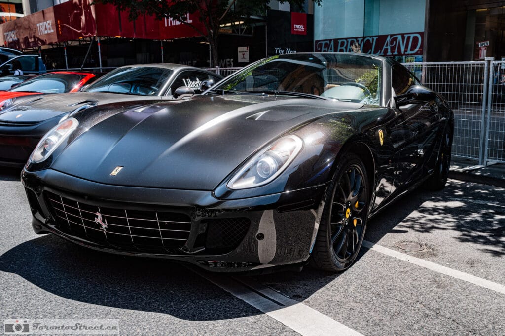 Ferrari 599 GTO--1001038 Front three-quarter view of a black Ferrari 599 GTO at a Yorkville curb, an older red Ferrari behind, Leica Q3