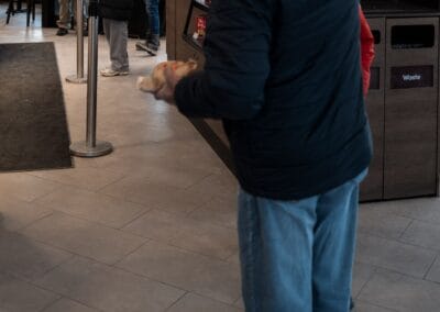 Man at the Tim Hortons entrance waving at a family arriving through the door, kids in Christmas hats, Leica Q3