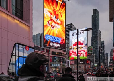 Colourful city street photography at Yonge-Dundas, a glowing Sonic billboard over the crowd, Leica Q3