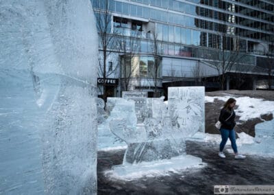 Blue ice sculptures on a melting snowbank outside a Yorkville coffee shop, a woman walking past, Leica Q2