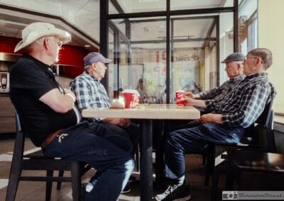Four older men in caps and a cowboy hat around a Tim Hortons corner table, tim hortons street photography, Leica Q3