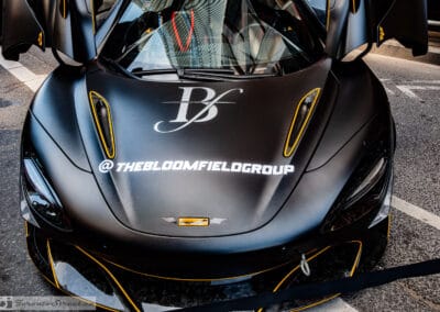 Matte black McLaren 720S hood with gold pinstripe and eye-socket vents, doors up, Leica Q3