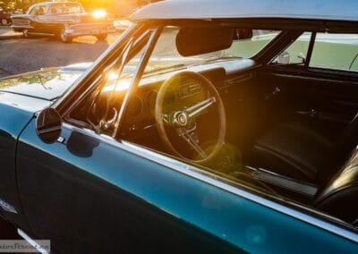 Sunburst flaring through the side glass over the steering wheel, gauges and black bucket seats, Leica Q3