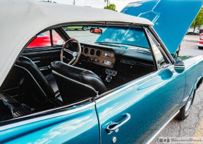 Dashboard, wood-rim wheel and black bucket seats over the door of a turquoise convertible, Leica Q3