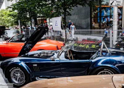 Blue open-top sports car beside an orange classic on Bloor Street, Yorkville crowd and storefronts, Leica Q3