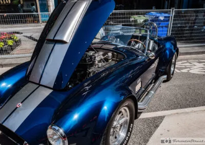 Polished velocity stack intake under the open hood of a blue convertible, Yorkville red carpet, Leica Q3