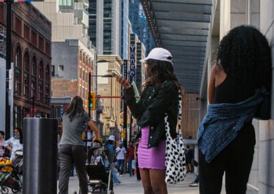 Young woman on a downtown side street, phone out, not in a hurry on a Sunday, Fuji X100V