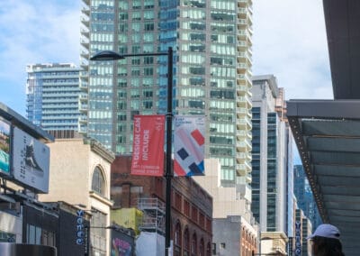 Downtown side avenue with a condo tower rising above, a woman in pink on a weekend afternoon, Fuji X100V