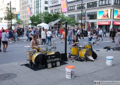 Griffin and Ryan drum duo performing in Yonge-Dundas Square, a loose weekend crowd watching, Fuji X100V