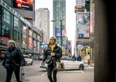 Woman in a yellow hoodie and yellow sneakers walking toward the camera at Yonge-Dundas Square, yonge street photography, Leica Q2