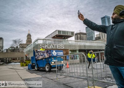 Man in a turban with headphones lifting his phone toward a Maple Leafs Zamboni at Nathan Phillips Square, Leica Q2