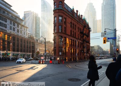 Gooderham Flatiron Building from the Church Street corner, golden hour light, a woman crossing the intersection, Leica Q2