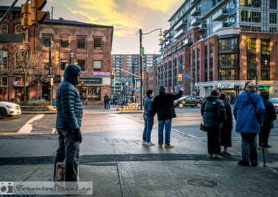 Group of young people at a market district intersection at golden hour, skateboarder in the foreground, warm evening light, Leica Q2