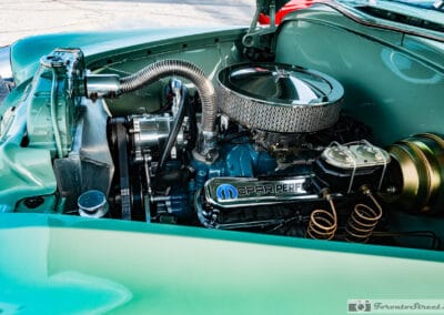 Small block V8 with chrome breather and coiled brake lines under a jade hood, Leica Q3