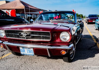 Low front view of the burgundy convertible with two Canadian flags on the windscreen, Leica Q3