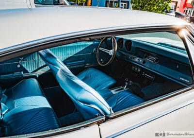 Turquoise vinyl seats, wood rim steering wheel and console shifter seen through the side glass, Leica Q3