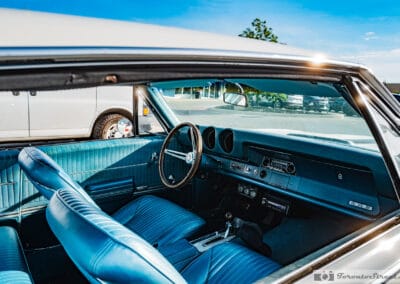 Blue interior and round dash gauges in low evening sun, a white van parked alongside, Leica Q3