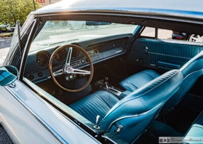 Wood rim wheel and gauge pods behind the driver's glass, turquoise seats and a chrome mirror, Leica Q3