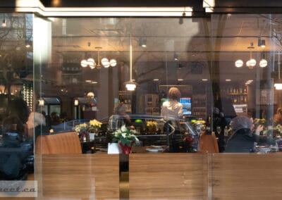 Panoramic view of a restaurant at night through Toronto windows, pendant lamps over the tables, Leica Q2