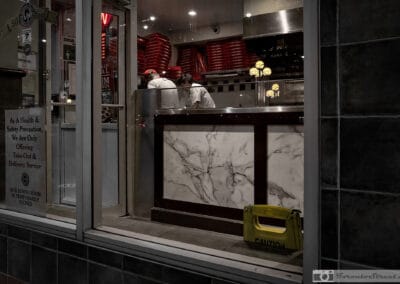 Toronto restaurant windows during the closures, two cooks behind a marble counter, take-out only sign, Leica Q2