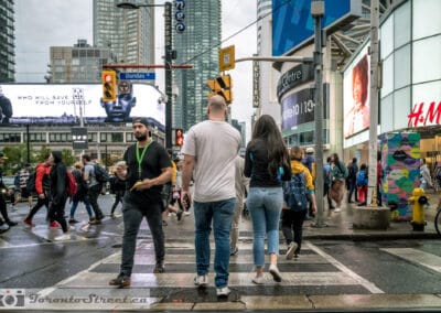 Crowds crossing at Yonge and Dundas in the Six, billboards and the H and M corner behind, Leica Q2