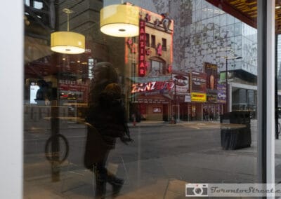 Zanzibar neon on Yonge reflected in Toronto windows at night, a figure walking past, Leica Q2