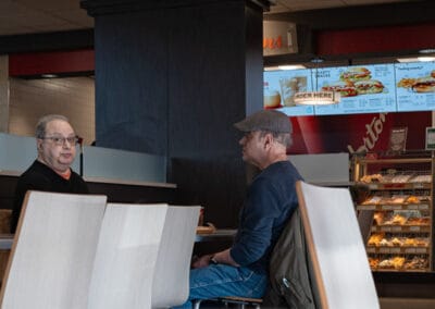 Wide panoramic strip of the dining room inside Tim Hortons, menu boards and a donut case, Leica Q3