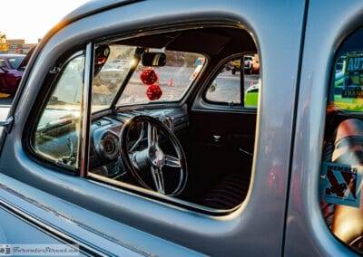 Through the driver's window: billet steering wheel, round gauges, red pleated seat and fuzzy dice in a 1948 Mercury, Leica Q3