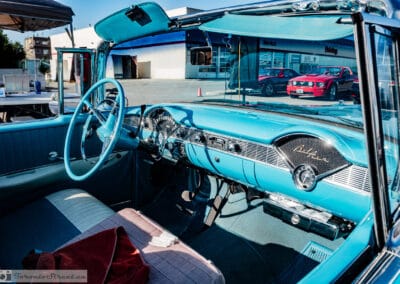 Turquoise dash and Bel Air script inside the open convertible, red Mustang reflected in the glass, Leica Q3