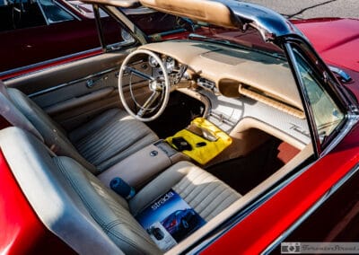 White steering wheel, ribbed metal dash and tan bucket seats of the 1961 Thunderbird, a yellow cloth on the console, Leica Q3