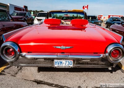 Rear deck of the red Bullet Bird with round taillights, tonneau headrests and a Canada flag on a pole, Leica Q3