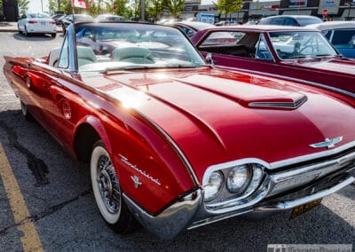 Low front three-quarter of the 1961 Thunderbird from the driver's side, sun burning on the red fender, Leica Q3