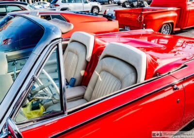 Tan headrest pads on the red tonneau cover over the rear seats, bucket seats and console ahead of them, Leica Q3