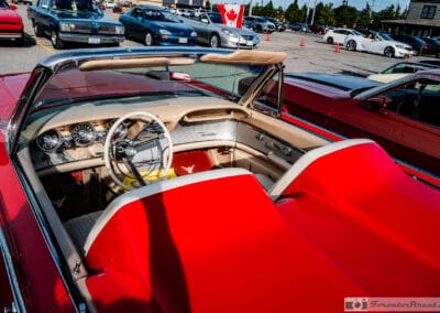 Looking down into the cockpit of the red convertible from above the tonneau, four round dials on the dash, Leica Q3