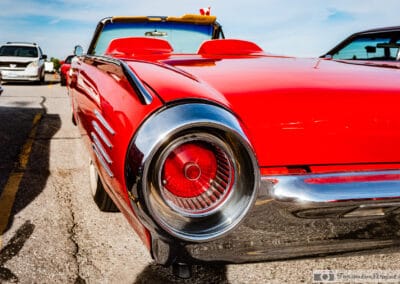 Close on a round chrome-ringed taillight and small fin of the red Bullet Bird, whitewall tire beside it, Leica Q3