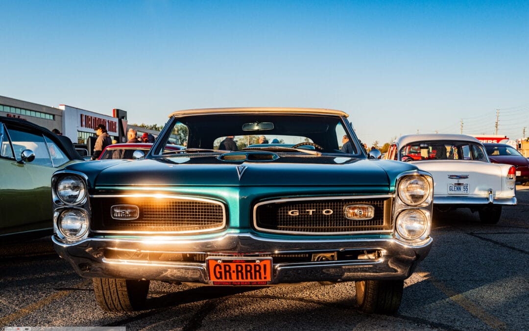 Head on at golden hour, low sun raking the chrome bumper and mesh grille of a 1966 GTO convertible, Toronto, Leica Q3