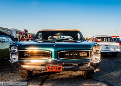 Head on at golden hour, low sun raking the chrome bumper and mesh grille of a 1966 GTO convertible, Toronto, Leica Q3