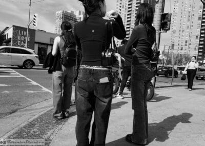People waiting to cross at a busy Toronto corner, a phone in a back pocket, condo towers behind, Leica Q3