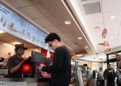 Young man paying at the Tim Hortons counter under the Canada Collection menu boards, GTA, Leica Q3