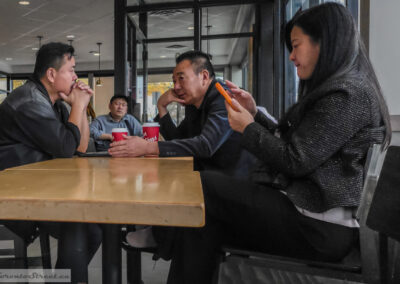 Best camera is the one you have, two men in close talk and a woman on an orange phone at a coffee table, taken on a phone